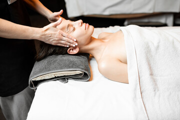 Young woman receiving a facial massage, relaxing at Spa salon