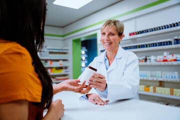 Mixed race client purchasing medication from senior female pharmacist