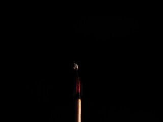 Burned match stick isolated on black background.