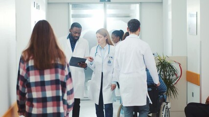 Hospital corridor. Multi-race diverse medical workers, doctors and nurses walking in hallway communicating wearing face masks. Pandemic. Coronavirus. Healthcare concept. - Powered by Adobe
