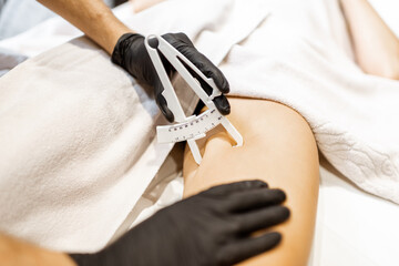 Determining the amount of sebum on female leg using medical caliper, close-up