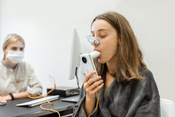 Young woman with doctor during a spirography test, measuring breathing movements with spirometer at...