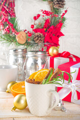 Traditional Winter Hot Alcohol Drink. Mulled Wine in a white Cup on the background of the kitchen table with Christmas decorations. 