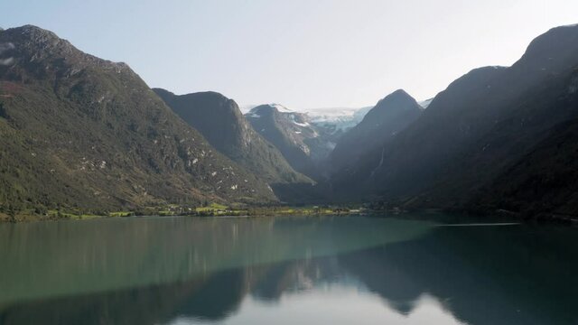 Aerial View of Glacial Lake Under Norwegian Mountains and Glacier on Summer Day. Oldevatnet, Norway, Drone Shot