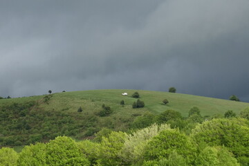 Obraz premium 豪雨前の丘を走る白い車