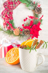 Traditional Winter Hot Alcohol Drink. Mulled Wine in a white Cup on the background of the kitchen table with Christmas decorations. 
