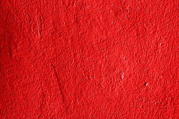 The texture of an iron metal painted bright red scarlet peeling paint old battered scratched cracked ancient rusty metal sheet wall with corrosion. The background.
