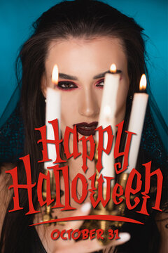 Young Woman In Veil With Blood On Face Near Burning Candles And Happy Halloween Lettering On Blue