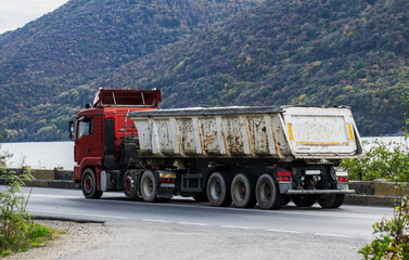Truck carrying coal, sand or other materials. The truck is on the road.