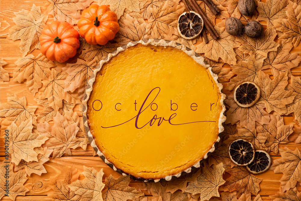 Wall mural top view of pumpkin pie with autumnal decoration near october love lettering on wooden background