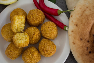 Falafel - authentic food of Israel. Fresh ingredients top view: plate of falafels, pita bread, parsley, lemon, parsley and red pepper.  Wooden table background. Healthy food photo. 
