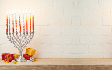 Jewish holiday Hanukkah concept with menorah, gift box and spinning top on wooden table