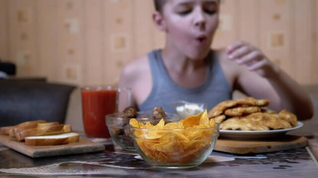Hungry Kid Hand Takes Crispy Golden Potato Chips from Plate. Junk Food in Dinner