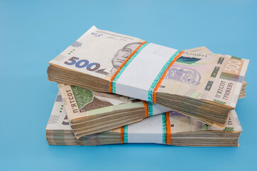 three bundles of hryvnia on a blue background. A stack with 500 hryvnia. Much money. Close-up.