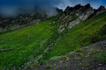 Obraz premium Mountain landscape Green mountains of Aibga ridge and rain cloudy sky Trekking in the mountains, active lifestyle, copy space, natural background