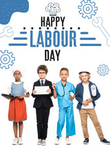 Fototapeta premium multicultural children in costumes of different professions near happy labour day lettering on white