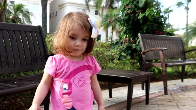 Garotinha brincando no jardim em tarde ensolarada e correndo em dire&ccedil;&atilde;o ao pai. Video em c&acirc;mera lenta.