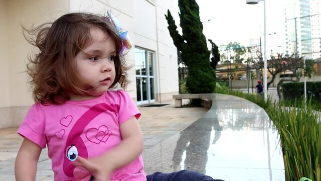 Garotinha sentada no banco e dan&ccedil;ando mexendo seus bra&ccedil;os. C&acirc;mera lenta.