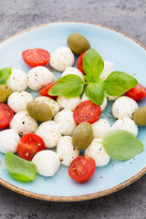 Delicious caprese salad with ripe cherry tomatoes and mini mozzarella cheese balls with fresh basil leaves.