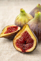 Closeup of two half cut figs, with more figs out of focus, on gray tablecloth, in portrait