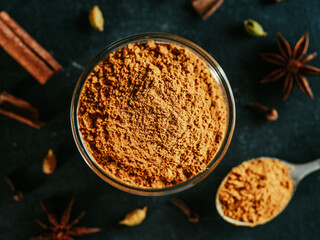 Indian or pakistani masala powder in spoon and small glass bowl. Close up view of homemade dry...