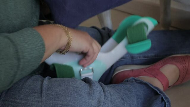 a woman puts a brace on her child with a disability, prosthetic