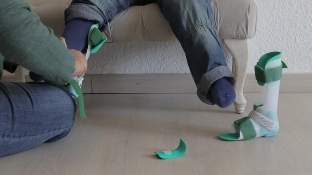 a woman puts a brace on her child with a disability, prosthetic