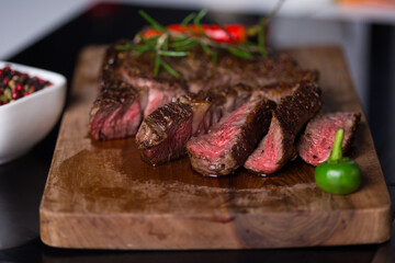 Sliced grilled meat steak Rib eye on meat fork and Pepper sauce on dark background