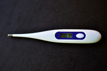 White and blue medical thermometer on a black background