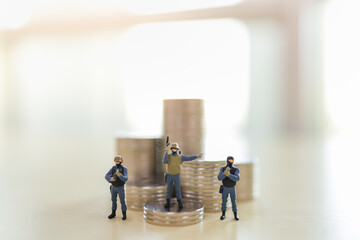 Business and Money Security Concept. Group of soldier with gun miniature figure people on stack of coins.