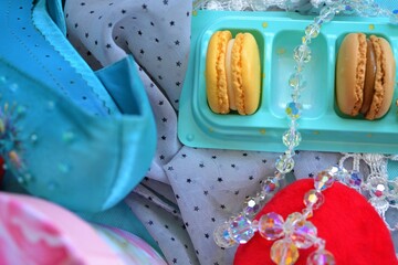 Red heart-shaped cushion, a box of macarons and a crystal necklace on a star print scarf