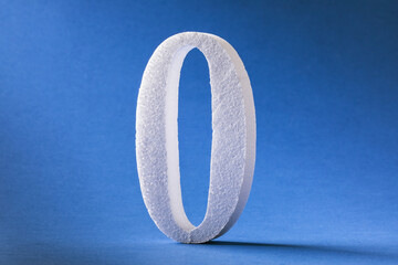 The digit is zero made of foam on a blue background. Concept on zeroing