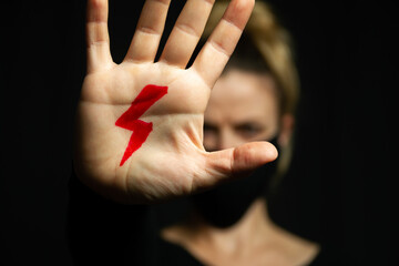 Woman with red lightning bolt drawn on her hand, symbol of the National Women's Strike against the...