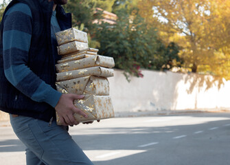 Man in a residencial neighborhood with a pile of presents christmas in a winter day. Winter 2020.