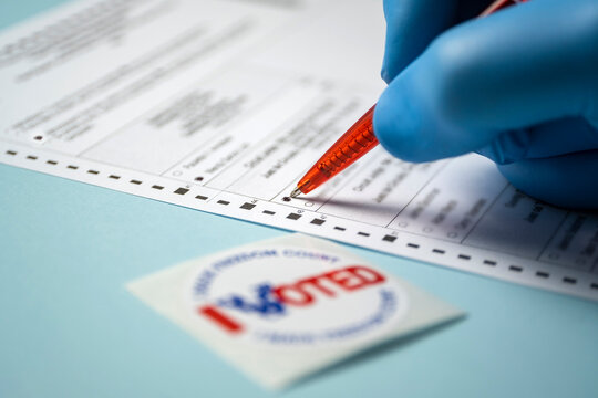 Badge and hand filling voting form on blue background