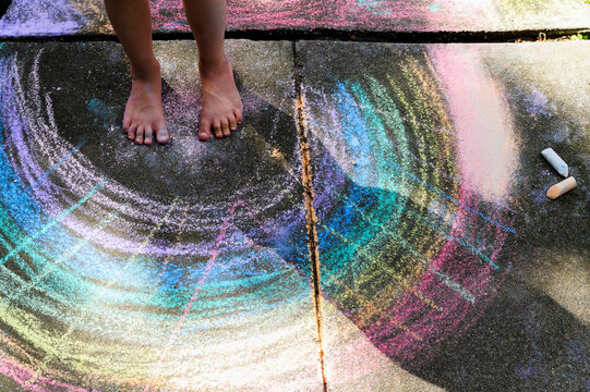 Low section of girl (6-7) standing on chalk drawing on pavement