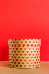 Valentine's Day concept. Paper round gift box with hearts print on red background. 