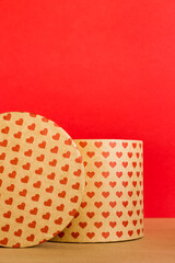 Valentine's Day concept. Paper round gift box with hearts print on red background. 