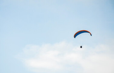Paraglider silhouette flying in foggy sky in Carpathian mountains. Popular tourist extreme sport activity