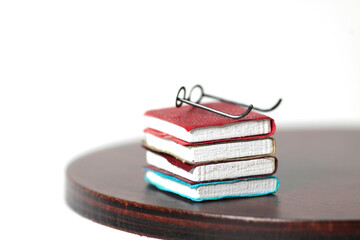 Doll house interior - a pile of books and glasses on the table isolated against white background. Horizontal image
