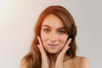 Naklejka premium Beautiful portrait of a young woman's head and hands near cheeks isolated white background
