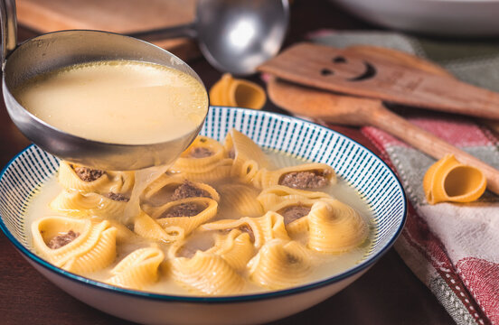 Primer plano de sopa de galets con una cuchara de sopa haciendo caer la sopa, el decorado est&aacute; hecho con los utensilios de cocina