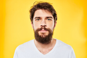 Obraz premium emotional bearded man in t-shirt cropped view yellow background studio