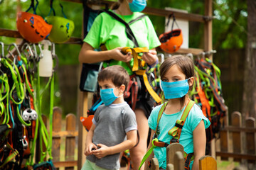 Obraz na płótnie Canvas Little children in disposable masks standing in the equipping point in the sky rope park
