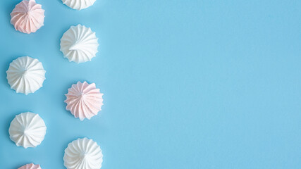 White and pink meringue cookies texture, blue background top view  with copy space  ,banner. - obrazy, fototapety, plakaty