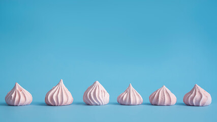  Pink meringue cookies texture  on blue  background top view.  Banner. - obrazy, fototapety, plakaty