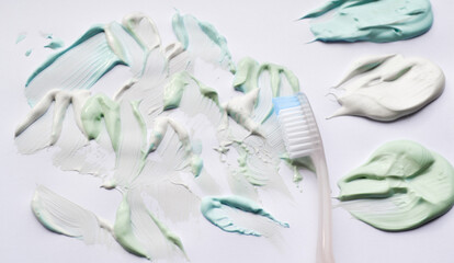 White toothbrush and toothpaste in three colors: green sweet mint, blue strong mint and white-whitening. White background, copy space. The concept of oral hygiene