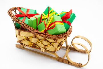 Old-fashioned wicker Santa sleigh with Christmas gifts wrapped in green paper with red ribbon