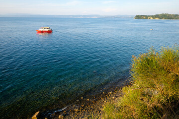 red boat on the sea approaching sea shore, lonely boat in slovenia