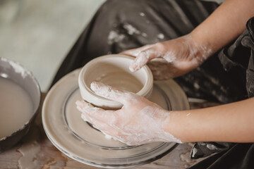 Woman hands creating earthen jar on the potter circle.